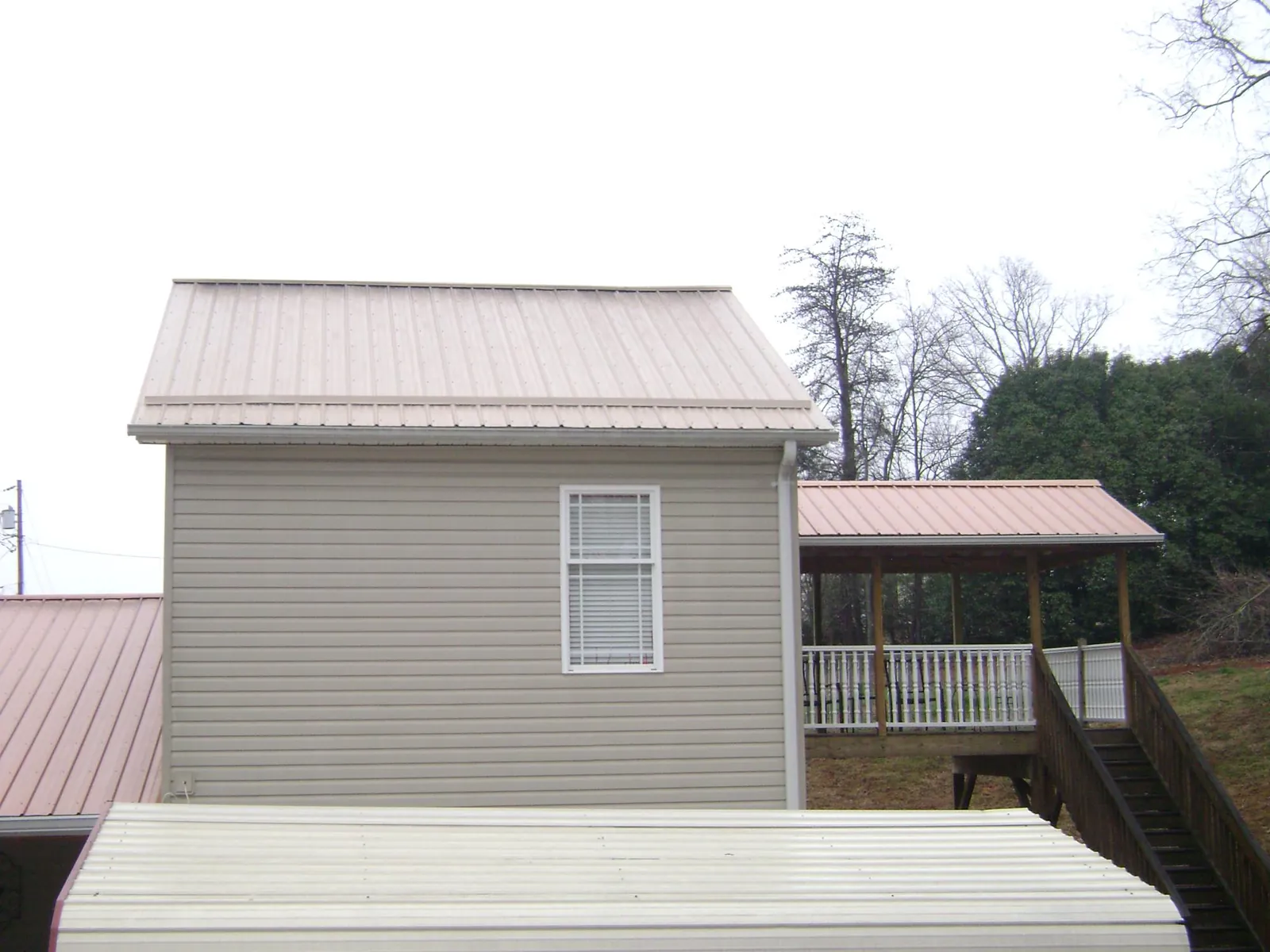 Tan metal roofs on a two story addition and attached porch, from a Roof Replacement job in Scottsville